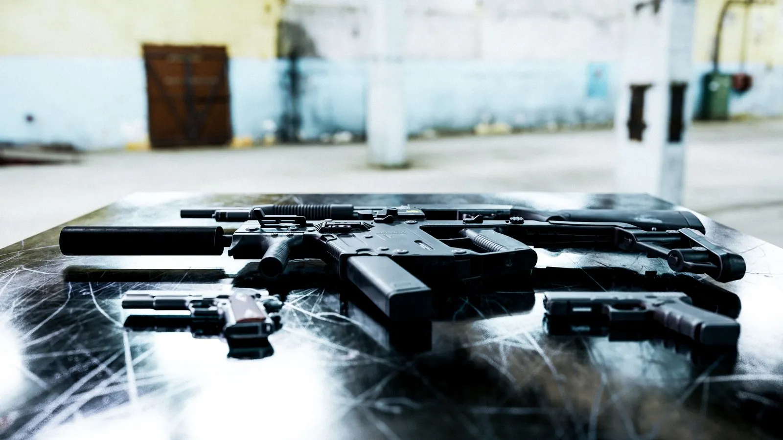 Subfusil junto a dos pistolas sobre una mesa metálica industrial, representación de un arsenal decomisado