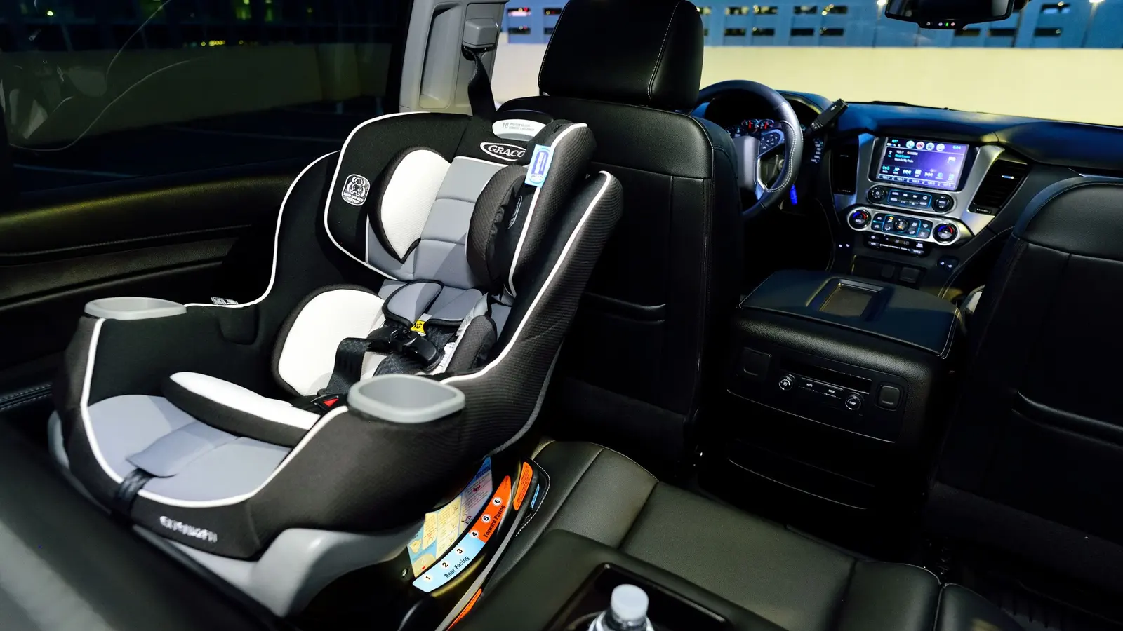 Interior de un auto con una silla infantil instalada en el asiento trasero, de noche